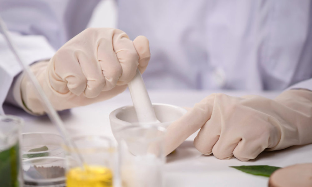 hands with glove while compounding a medicine