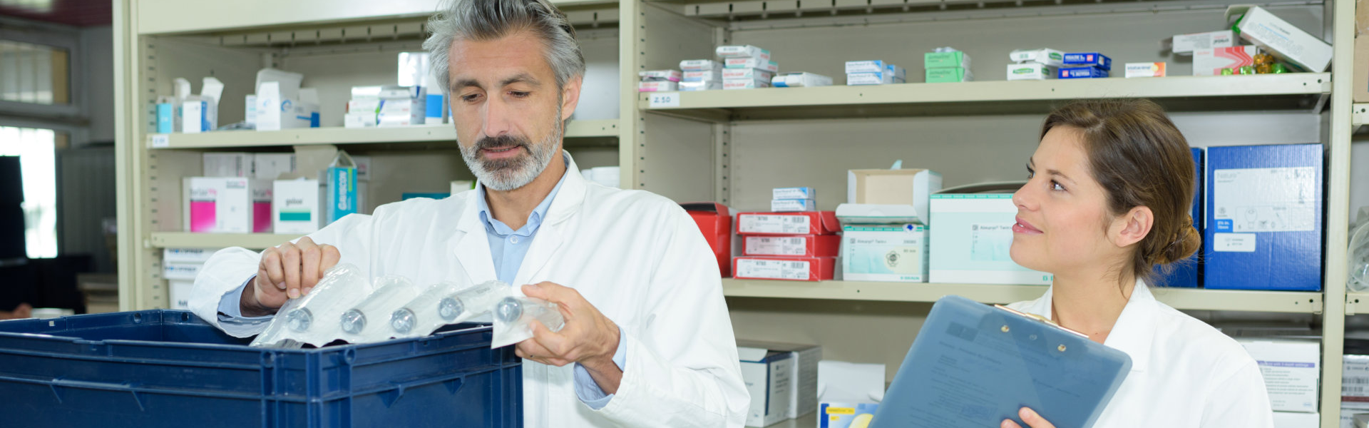 Male and female pharmacists maintaining checklist at counter in pharmacy pharmacist