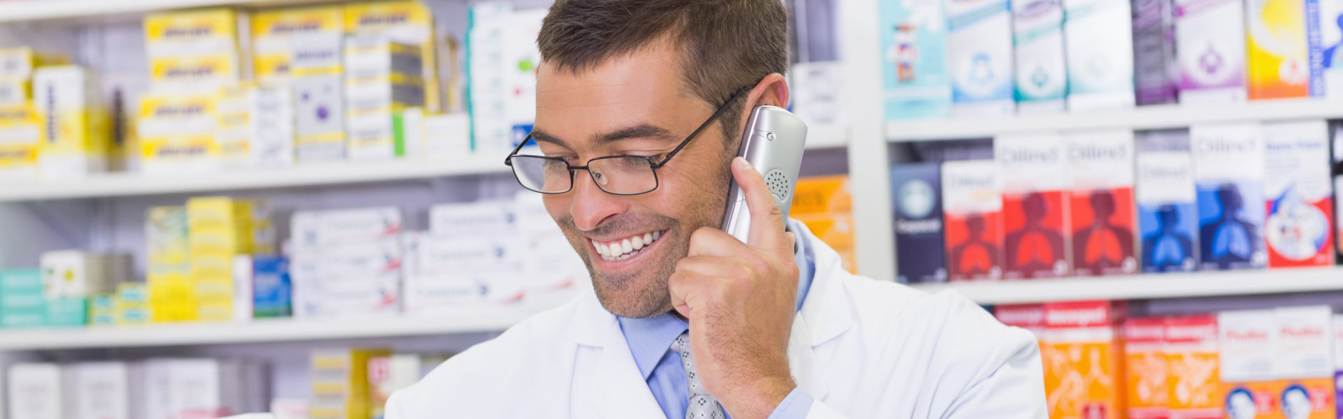 Happy pharmacist on the phone at the hospital pharmacy